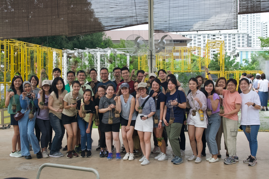 A corporate team taking a group photo at the end of a sustainable team bonding Kokedama crafting workshop at City Sprouts.