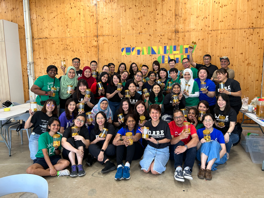 A group of smiling people having fun at a corporate team bonding eco-enzyme workshop at City Sprouts.