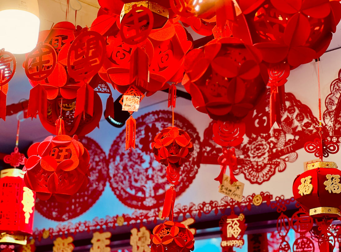 Photograph of red traditional Chinese New Year decorations, including paper cuttings and lanterns. Photo by Aerian Yu on Unsplash.